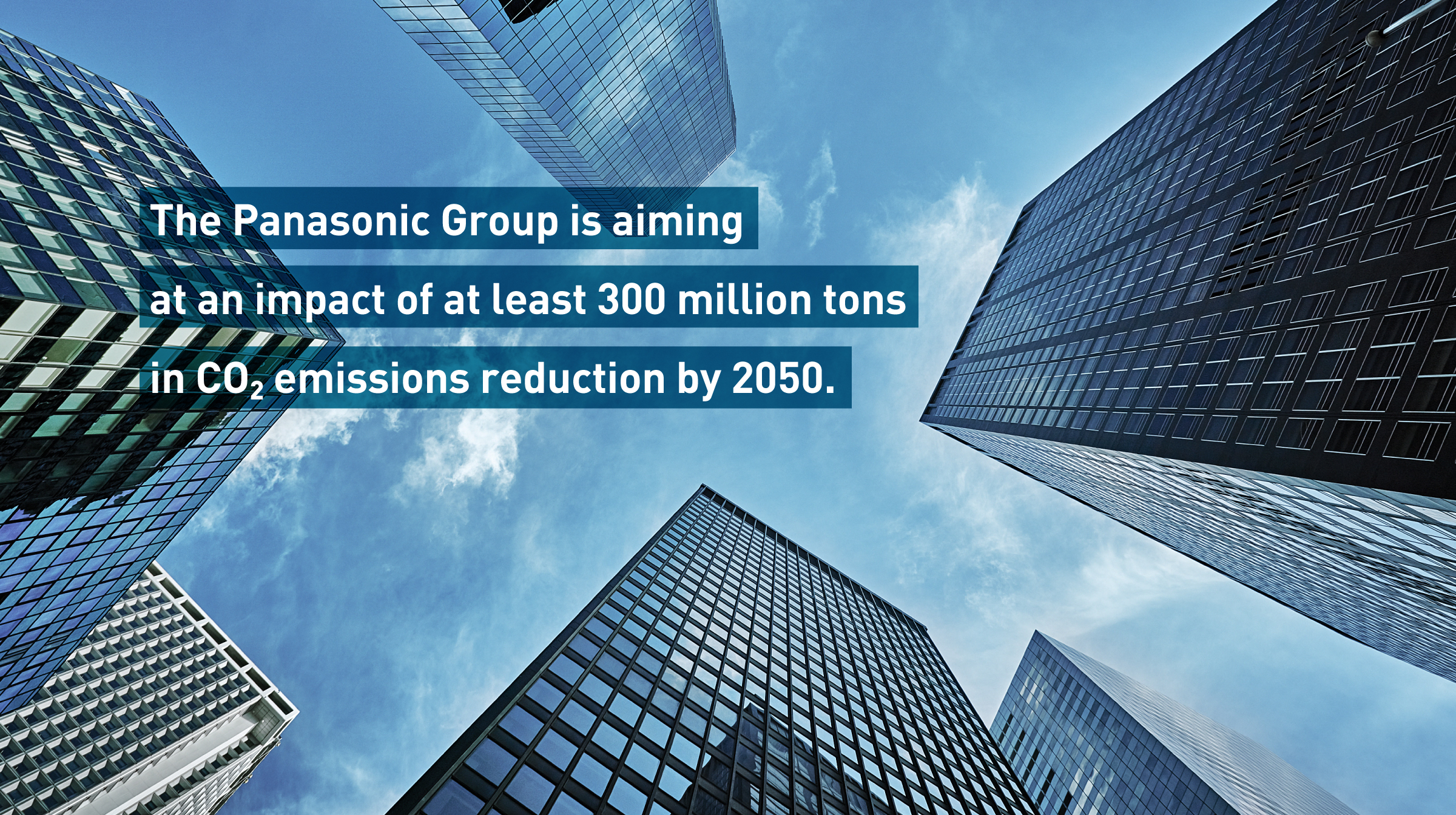 The Panasonic Group is aiming at an impact of at least 300 million tons in CO2 emissions reduction by 2050. Background photo: Tall skyscrapers viewed from below against a blue sky.