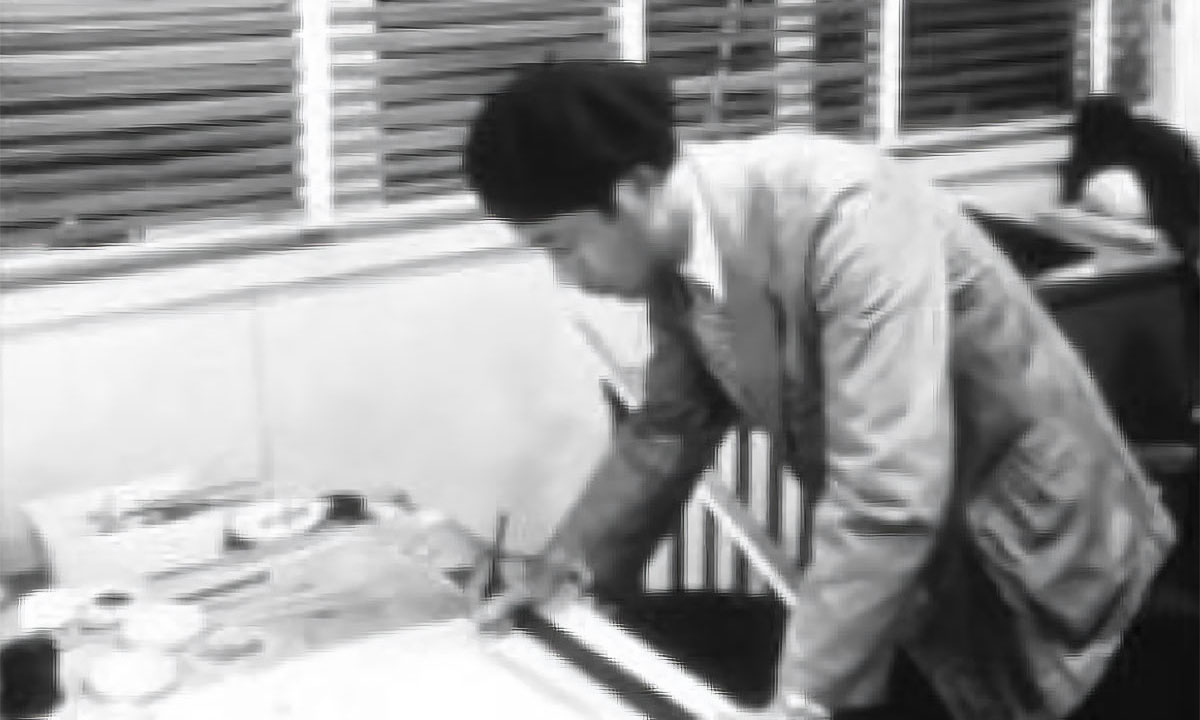 Black and white photo of the first design leader thinking in front of a drawing