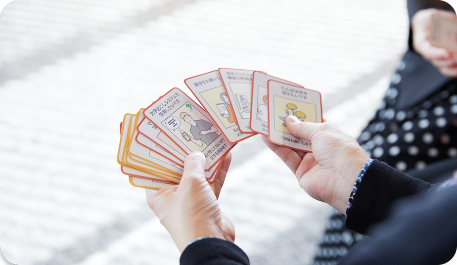 Close-up photo of a person holding Communication Support Cards in both hands.