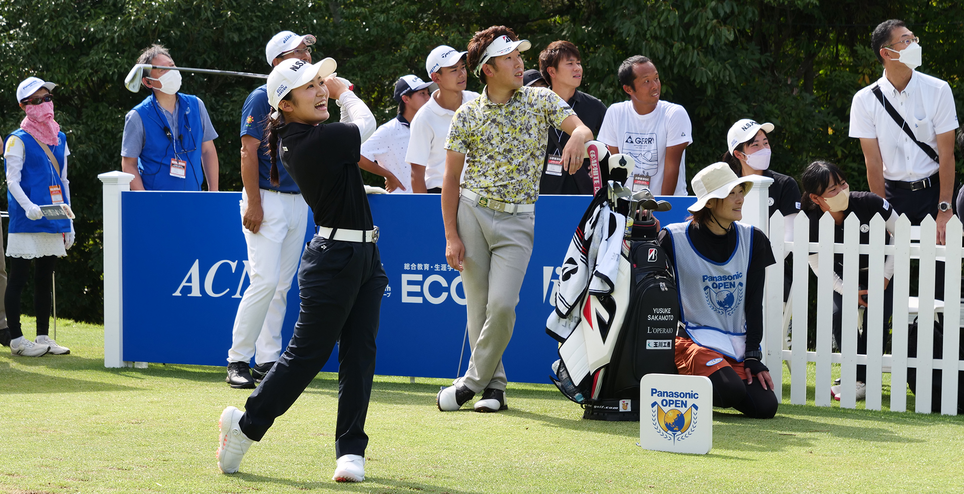 選手が見守る中、笑顔でスイングする女子生徒