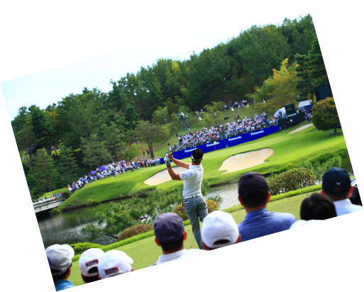 ティーイングエリアから、池の向こうのギャラリーホールに向かってティーショットを打つ選手