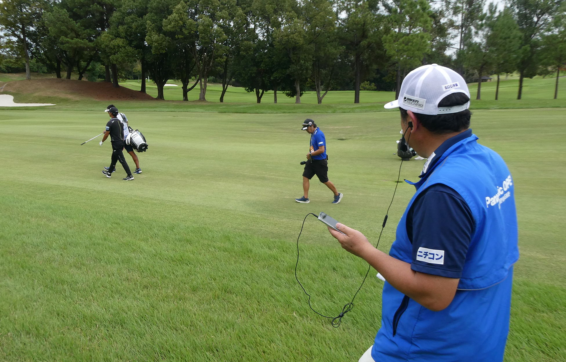 イヤホンとマイクを着けて解説する小岸キャディ