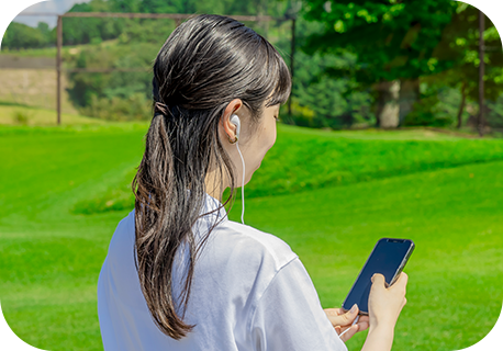 スマホにイヤホンをつけて18番ホールライブ解説を聞く体験者