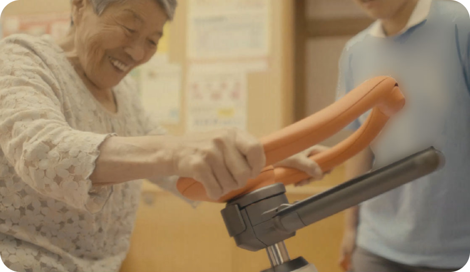 写真:歩行トレーニングロボットを使っている笑顔の老婆