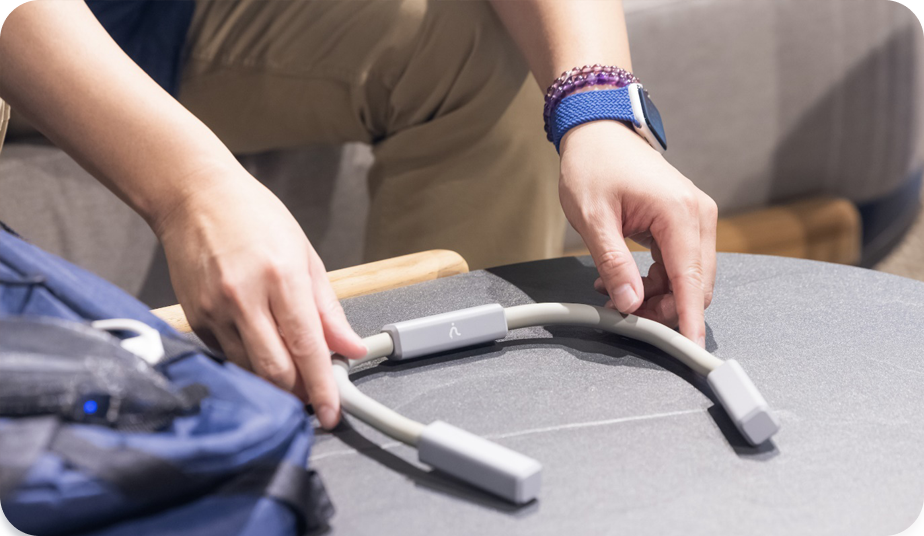 写真:シルバーのU字に曲がったコデカケデバイスを両手で手に取る人の手元の写真。