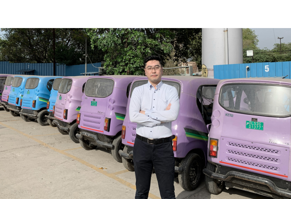実証実験に使用した三輪のEモビリティ電動車両を背景に、腕組みをする岩隈智行さん
