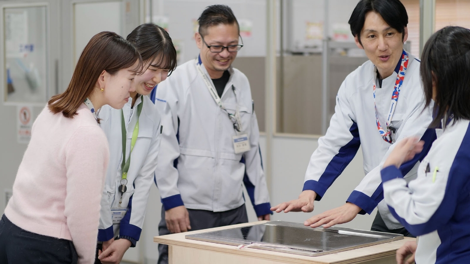写真：IHの製品を囲み、社員同士が笑顔で意見を交わす様子