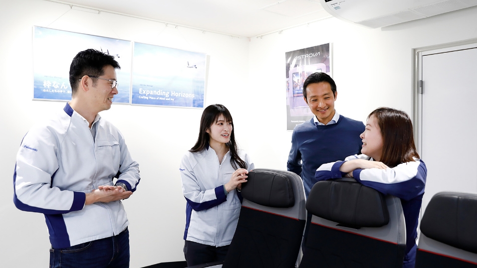 写真：アビオニクス関連の機材を囲み、社員同士が笑顔で意見を交わす様子