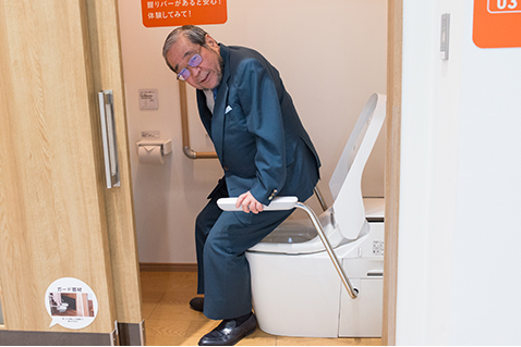 写真:アームレスト付きのトイレを体験する天野さん