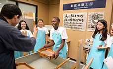 Photo: Instructor praising kids making Japanese paper well
