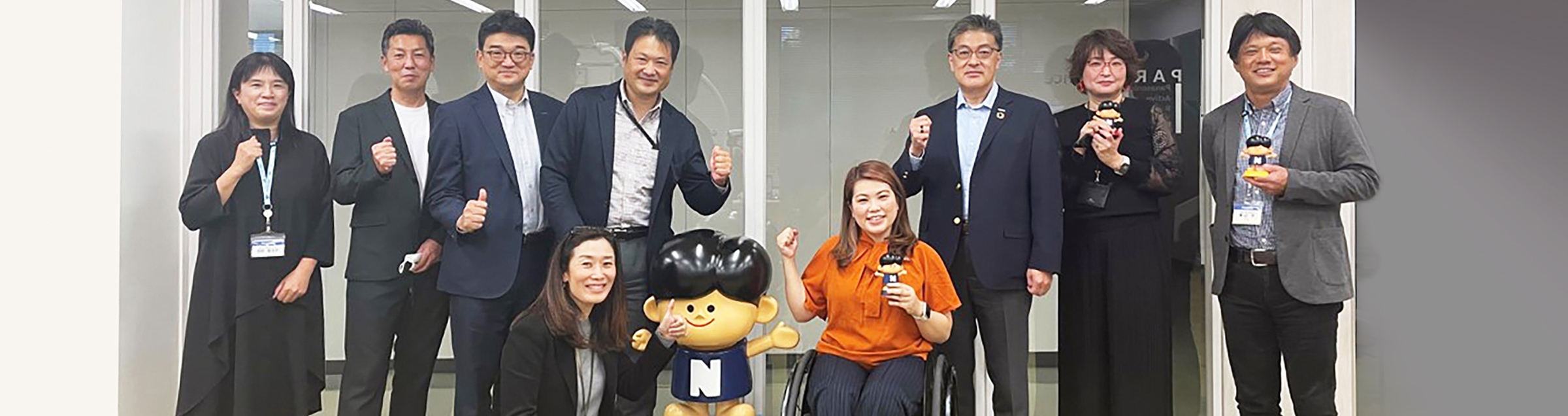 Photo: Eri Yamamoto fist pumping the air with a National Boy doll in her hand, surrounded by workshop participants.