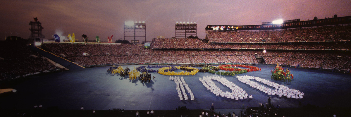 照片：在亚特兰大奥运会开幕式中，在体育场中央区域绘制的五环标志和由人组成的100的数字