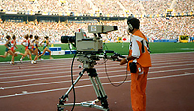 照片：摄影师在巴塞罗那奥运会会场使用数码摄影机拍摄田径选手的情景