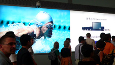 Photo: People watching a competition on a large Panasonic electronic billboard installed at Beijing Capital International Airport