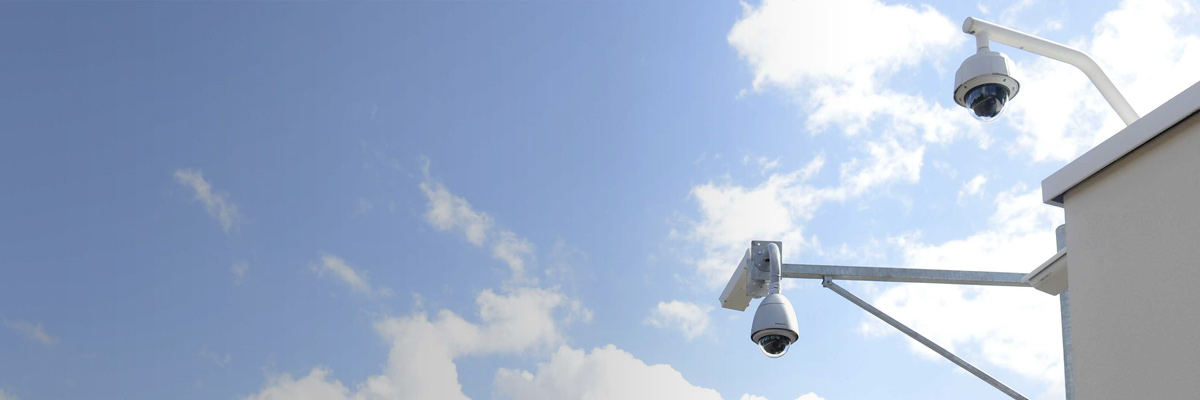 Photo: Outdoor security camera with housing and dome-type security cameras installed on the outside of a building
