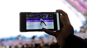 Photo : Utilisation d’un smartphone dans les gradins d’un site des compétitions pour visionner des images de patinage artistique sur un système de diffusion multi-vidéo