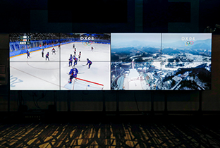 写真：2分割されたシステムディスプレイに映し出されたアイスホッケー競技映像とスキー競技会場の全景
