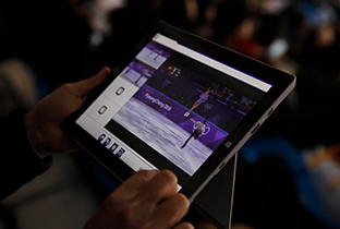 照片：在赛场观众席上使用平板电脑，观看发布的花样滑冰影像的情景