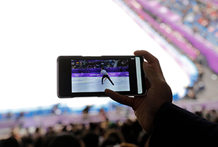 照片：在赛场观众席上使用智能手机，观看发布的花样滑冰影像的情景
