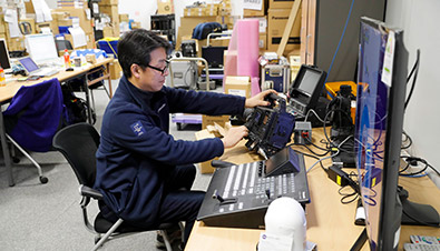 Photo of staff performing maintenance on camera recorders and other equipment at the Panasonic support room inside the International Broadcast Centre
