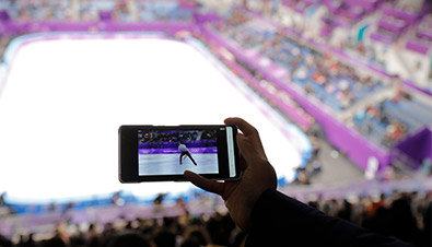 写真：競技会場の観客席でスマートフォンを使用し、動画配信されたフィギュアスケートの映像を観ている様子