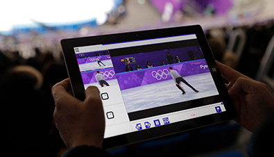 写真：競技会場の観客席でタブレットを使用し、専用のアプリからマルチ動画配信システムでフィギュアスケート映像を観ている様子