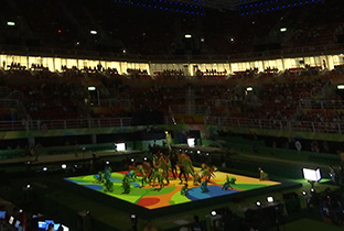 照片：使用DLP投影机在里约奥运会的体操比赛会场地面上投影光芒，表现表演者动作的体操开场画面