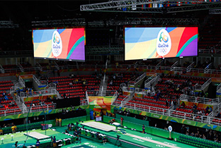写真：リオオリンピックの体操競技会場の天井中央に設置された複数の大型映像表示装置に映し出されたリオオリンピックロゴ