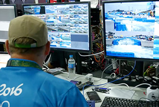 写真：複数のモニターに映るカヌー競技中の映像を見るスタッフ