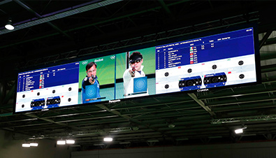 照片：设置在里约奥运会射击比赛会场的大型影像显示装置上显示的气枪比赛画面及时间和比分
