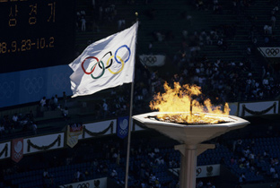照片：首尔奥运会会场上升起的五环标志旗帜和燃烧的圣火台
