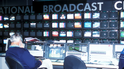 照片：工作人员在IBC（国际广播中心）使用大量显示器和播放设备进行工作的情景