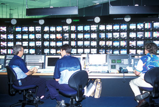 照片：多名工作人员在IBC（国际广播中心）使用大量显示器进行工作的情景