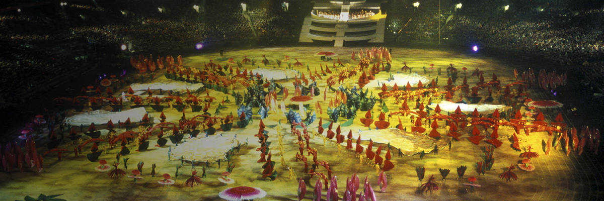 写真：メインスタジアムでのシドニーオリンピック開会式で色鮮やかな衣装を着た人々が登場するセレモニーの全景
