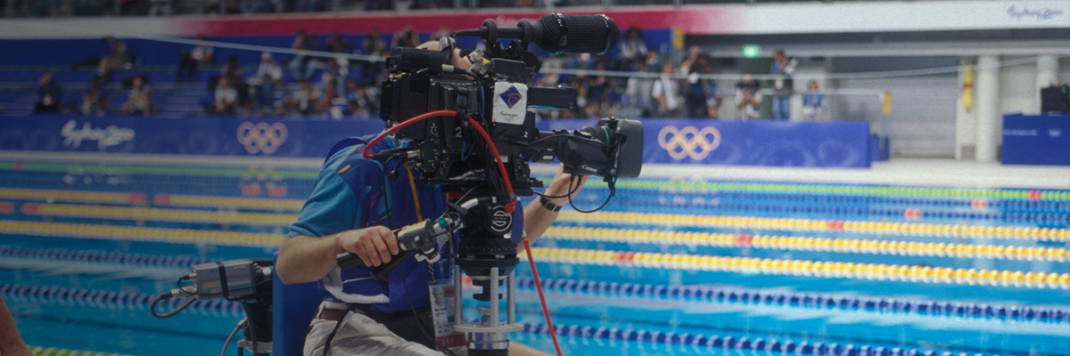 照片：摄影师在悉尼奥运会游泳比赛会场使用摄影机进行拍摄的情景