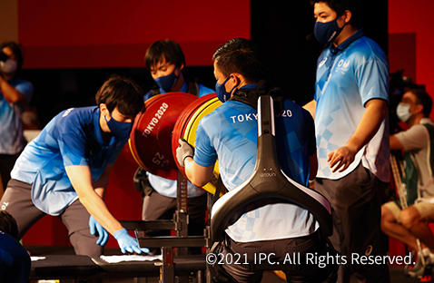 写真：東京2020パラリンピックでパワーアシストスーツ「ATOUN MODELY」を装着しバーベルの重りを交換する補助員