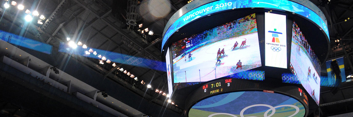 照片：设置在温哥华冬季奥运会会场顶棚中央的多台大型影像显示装置上显示的冰球比赛画面和记分板