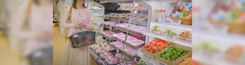 写真：スーパーで買い物をする女性。冷蔵ショーケースには生鮮食品が陳列されている