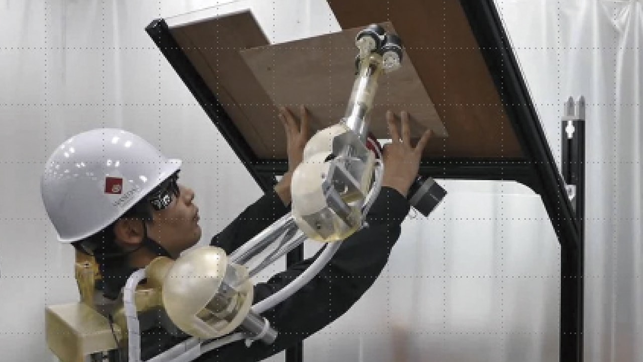 写真：身体に装着されたロボットアームが板を支えて固定する様子
